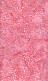 A close-up of a pink cotton batik fabric with scattered small white and pale blue circular spots and a mottled pattern