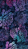 A close-up of batik fabric featuring a repeating floral pattern in purple, pink, and teal over a dark navy blue background.