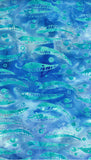 A close-up of a blue and teal patterned cotton batik fabric featuring a repeating watercolor-style design of  gum leaves and nuts