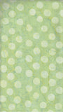 A close-up of a light green batik fabric with a repeating pattern of large, circular spots pale lime green.