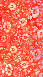 A close-up of a red-orange floral pattern with white and pale yellow flower motifs on a textured background.