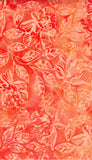 A close-up of a batik fabric pattern featuring stylized hibiscus flowers and leaves in coral red and orange tones with a watercolor wash effect.