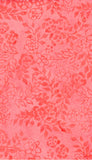 A close-up of a coral pink batik fabric  pattern featuring a darker coral-red floral and vine motif.