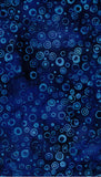 A close-up of a dark blue patterned Batik fabric featuring a repeating motif of hand-drawn concentric circles in lighter blue and navy tones.