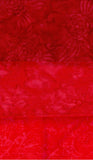 A close-up of a bright red textured fabric with a subtle tonal floral or damask pattern.